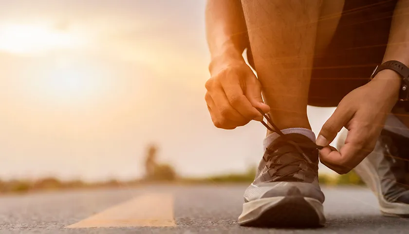 Descubre la importancia de la elección del calzado para la actividad deportiva. hombre atándose la zapatilla para correr