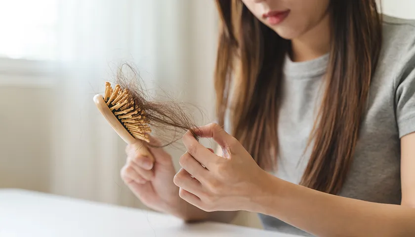 En Farline, encontrarás consejos para ayudar a evitar la caída del pelo estacional. mujer observa la caída de su cabello en un cepillo