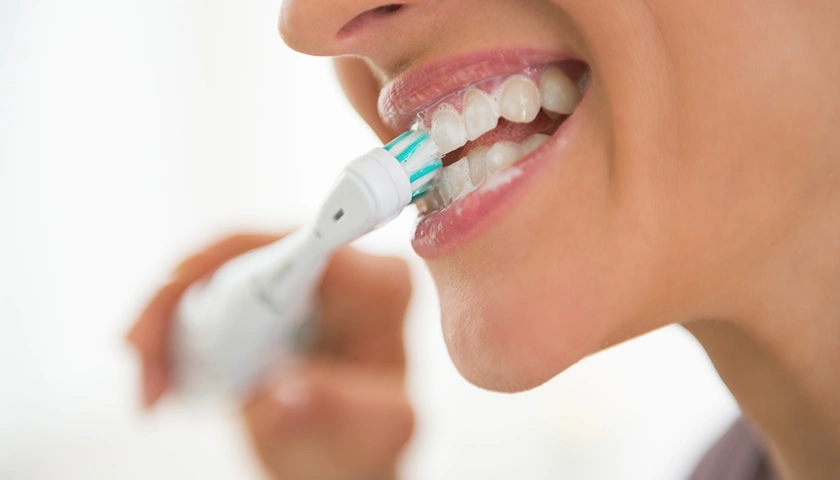 mujer_usando_cepillo_dientes_electrico.webp